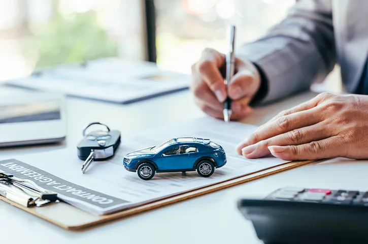 車の鍵とミニカーが乗っている書類に記入をしている